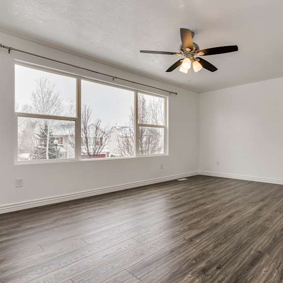 an empty living room with a ceiling fan and a large window