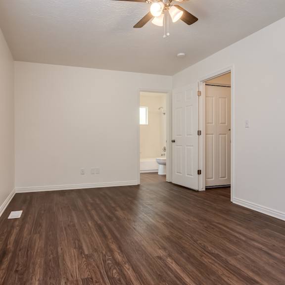 an empty living room with wooden floors and a ceiling fan