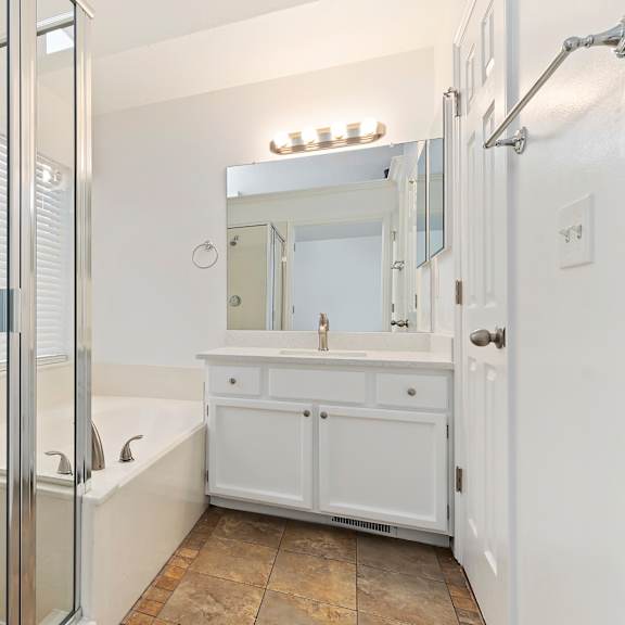 a white bathroom with a glass shower door and a white sink vanity.