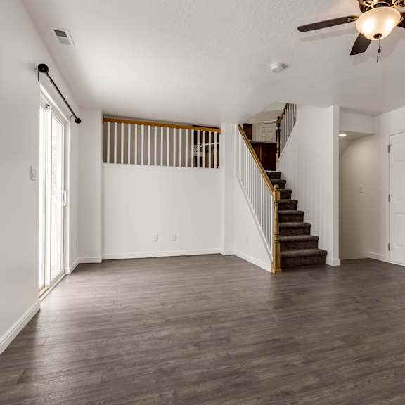 a spacious room with a staircase and a ceiling fan.