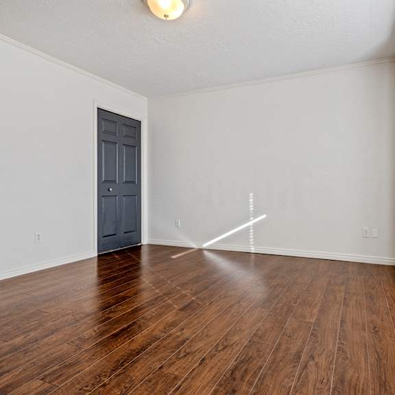 an empty living room with wood floors and a blue door