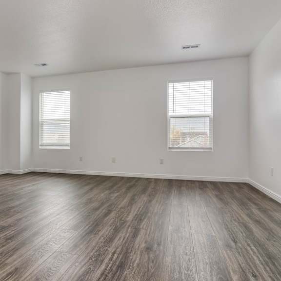 a room with wooden flooring and a window with blinds.