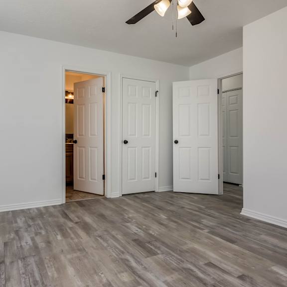 a room with a ceiling fan and three doors.