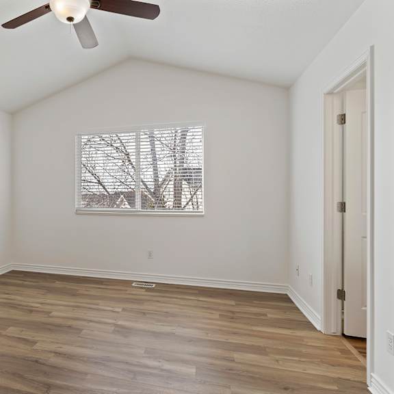 a room with a ceiling fan and a window with a view of a building.