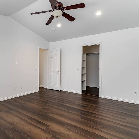 a room with a ceiling fan and wooden floors.