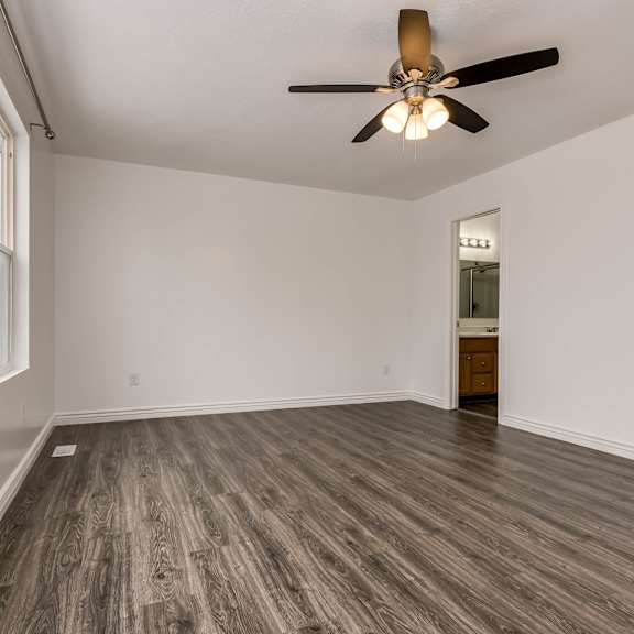 an empty living room with a ceiling fan and a window