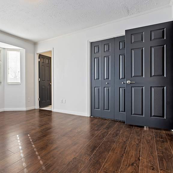 an empty living room with wood floors and a black door