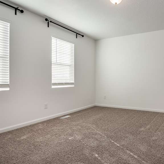 a room with a carpeted floor and a window with blinds.