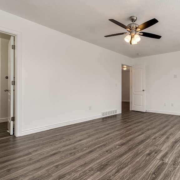 an empty living room with white walls and a ceiling fan