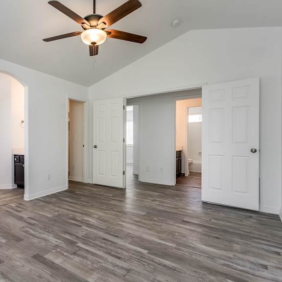 an empty living room with white walls and a ceiling fan