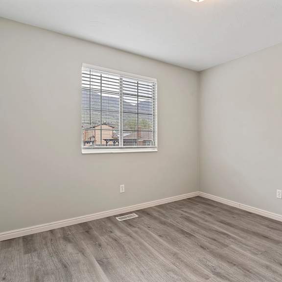an empty room with wood floors and a window