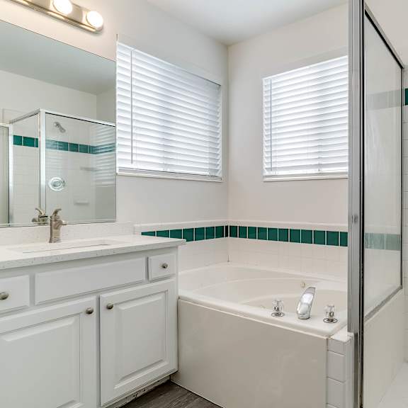 a white bathroom with a glass shower door and a white tub.