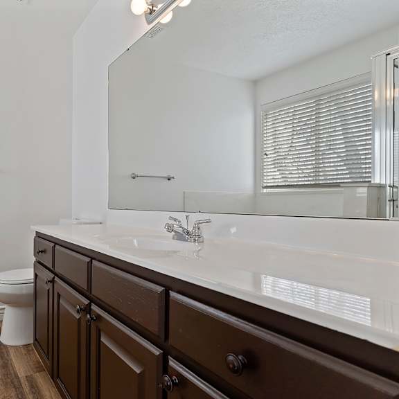 a bathroom with a white counter top and brown cabinets.