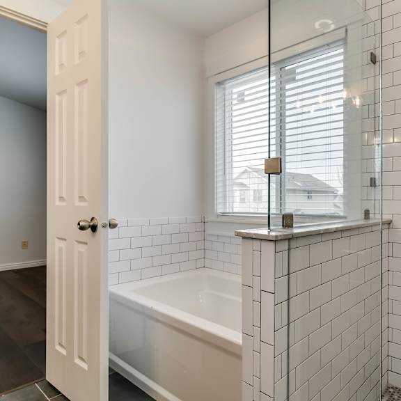 a white tiled bathroom with a glass shower door.