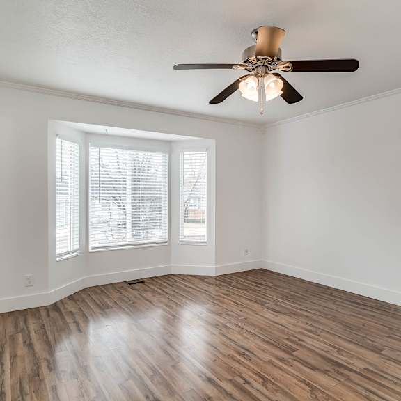 a room with a ceiling fan and wooden flooring.
