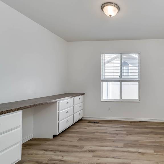 an empty kitchen with white cabinets and a window
