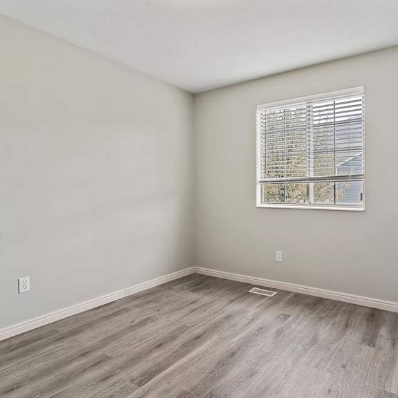 an empty room with wood floors and a window
