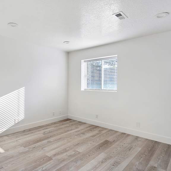 an empty room with white walls and wood floors and a window