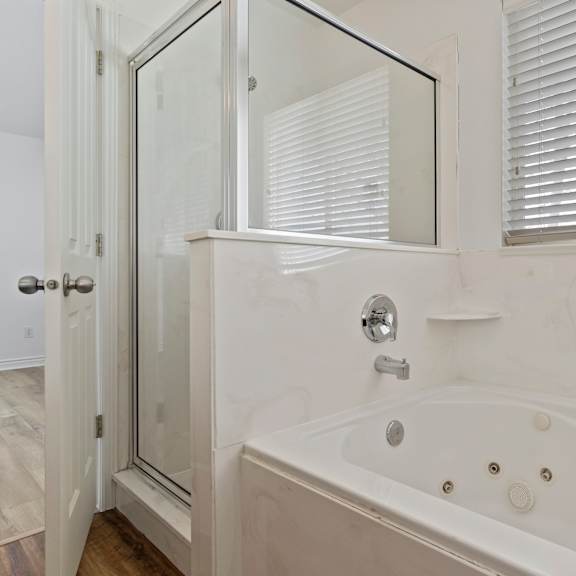 a white bathroom with a tub and a shower.