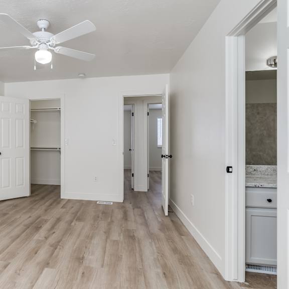 a room with a ceiling fan and wooden flooring.