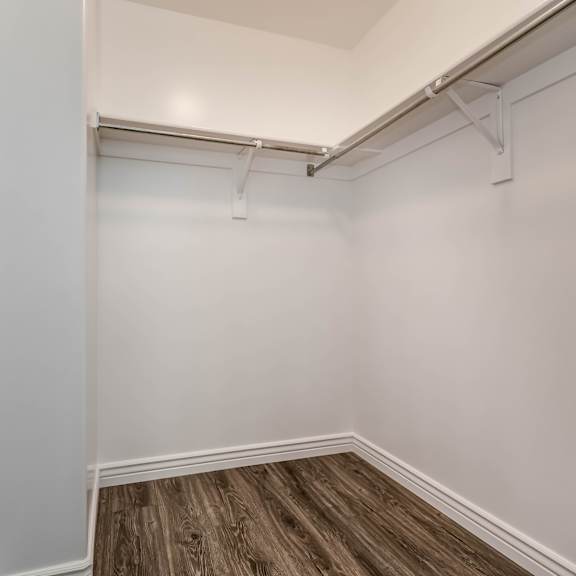an empty room with white walls and a wooden floor and a white walled closet