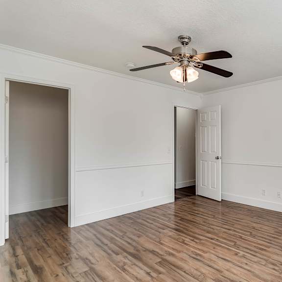 a room with a ceiling fan and wooden flooring.