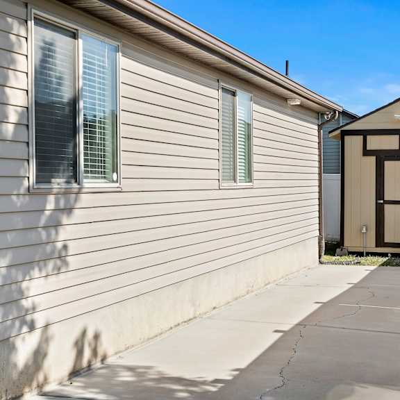 a small building with a brown door is situated next to a house.