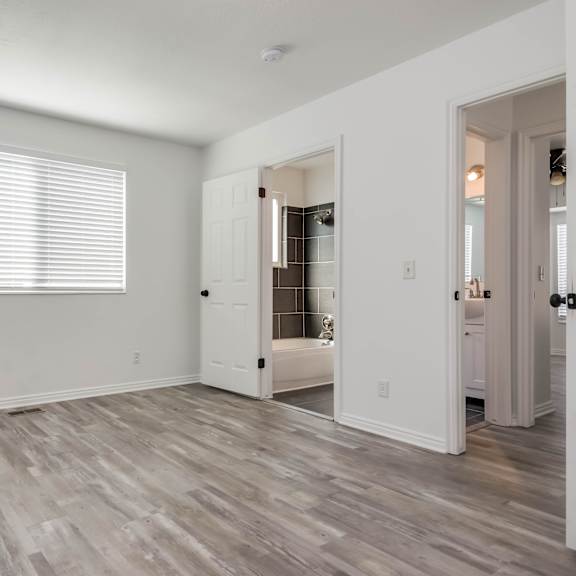 a room with a wooden floor and a window with blinds.