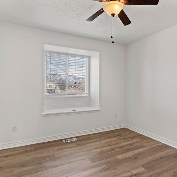 a room with a ceiling fan and a window with blinds.