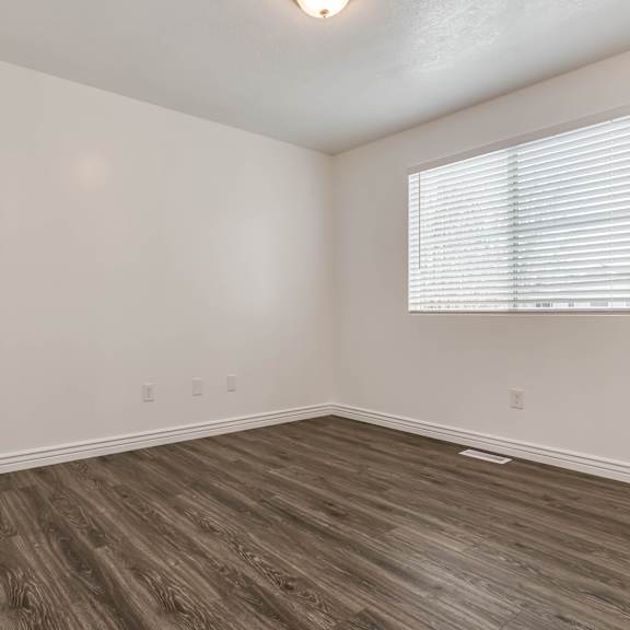 an empty room with wood flooring and a window