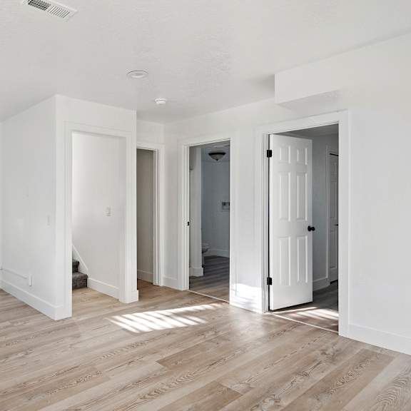 a renovated living room with white walls and wood floors