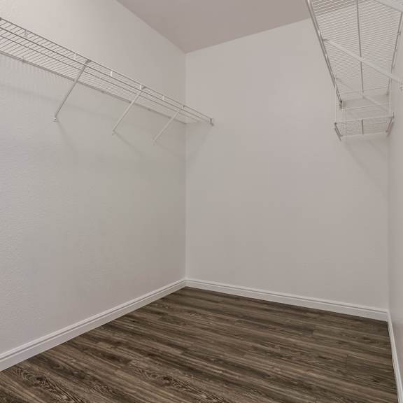 a room with white walls and wood flooring with two metal racks on the wall.