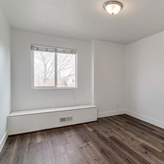 a room with a window and wooden floors.