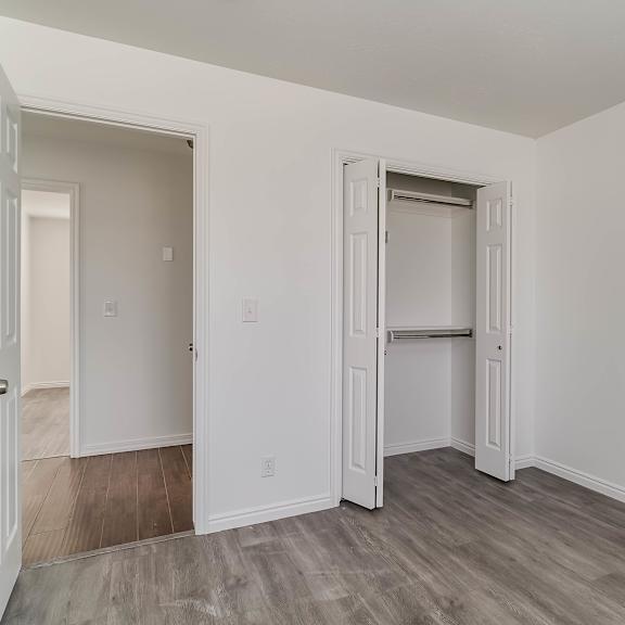 a room with white walls and a grey floor with a door open.