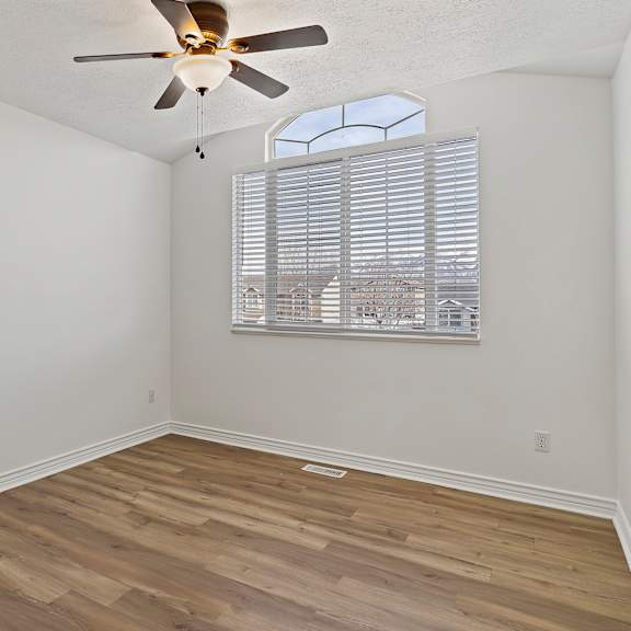 a room with a ceiling fan and a window with blinds.