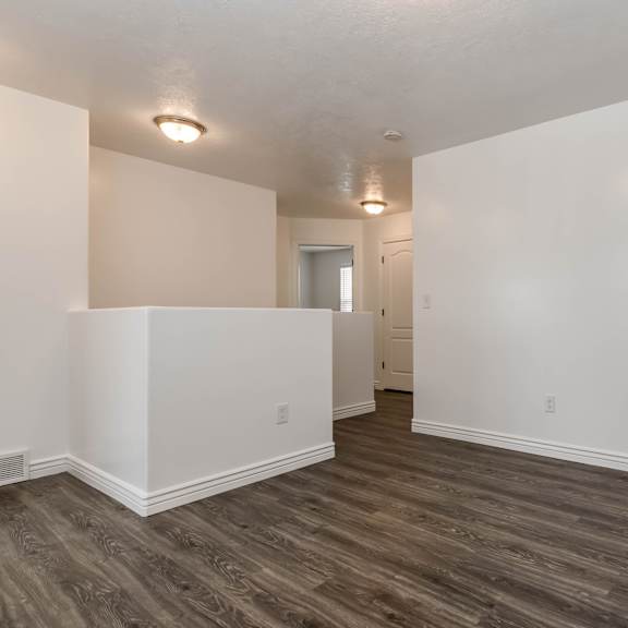 an empty living room with white walls and wood flooring