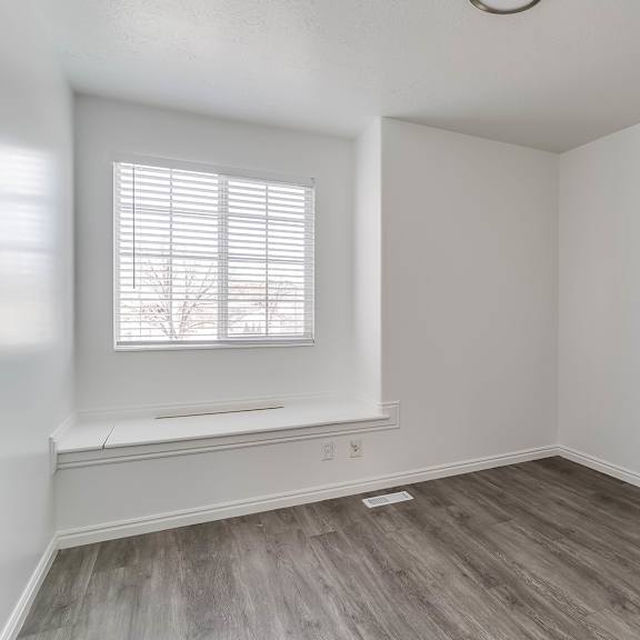 a room with a window and wooden flooring.