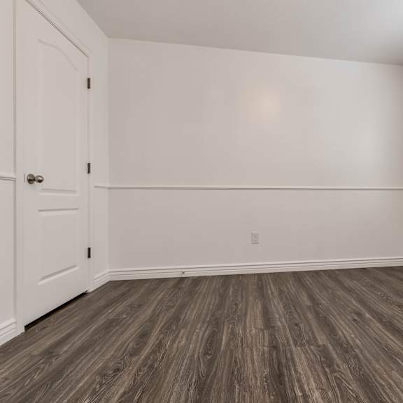 an empty room with white walls and wood flooring and a window