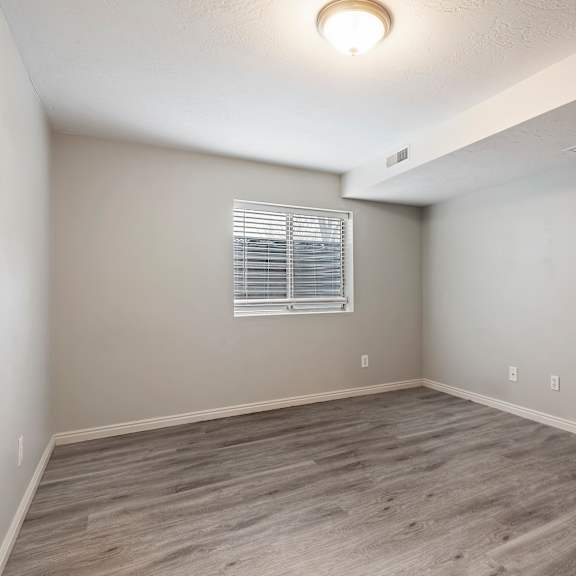 an empty living room with wood flooring and a window