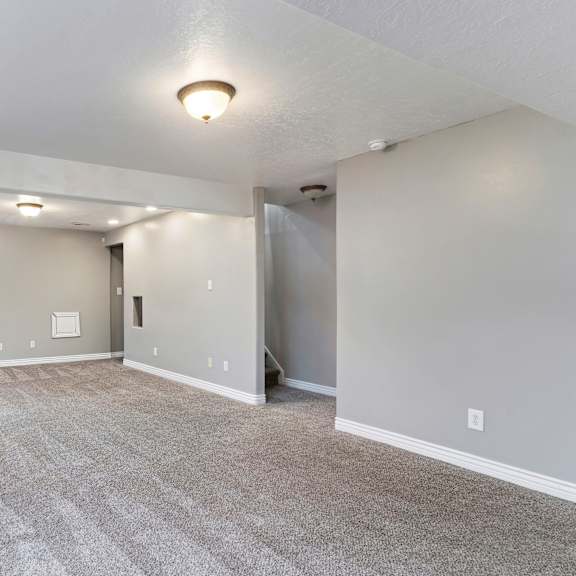 a spacious room with grey carpeting and white walls.