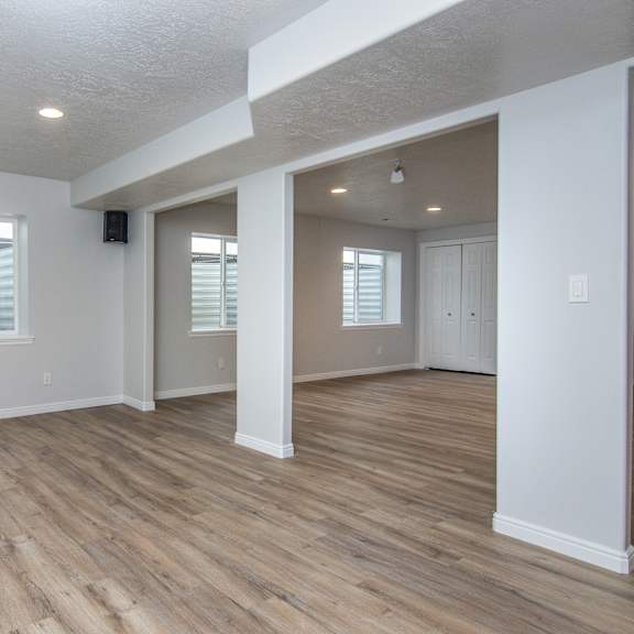 the living room and dining room of an empty house with wooden floors and white walls
