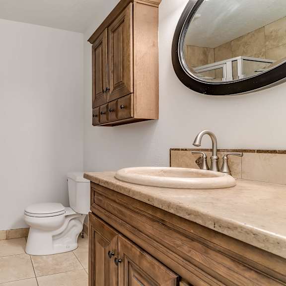 a bathroom with a toilet, sink, and mirror.