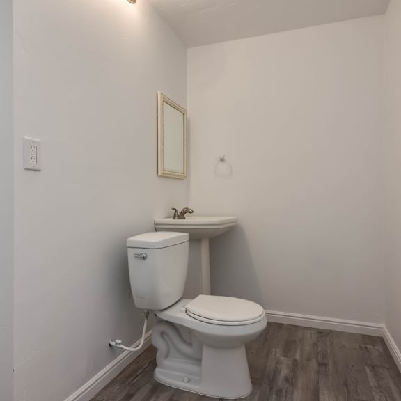 a white toilet with a sink and mirror in a small bathroom.