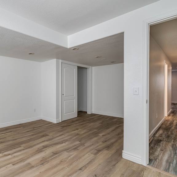 an empty living room with white walls and wood flooring