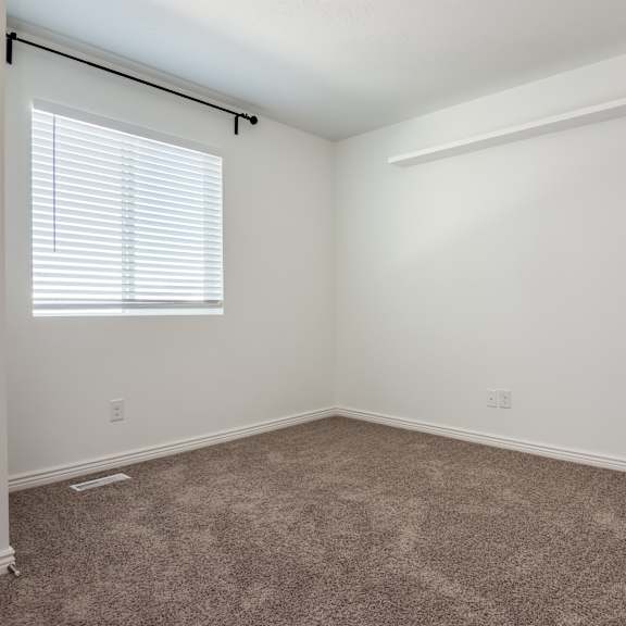a room with a carpeted floor and a window with blinds.