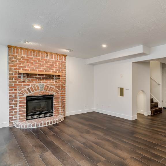 a room with a brick fireplace and wooden floors.