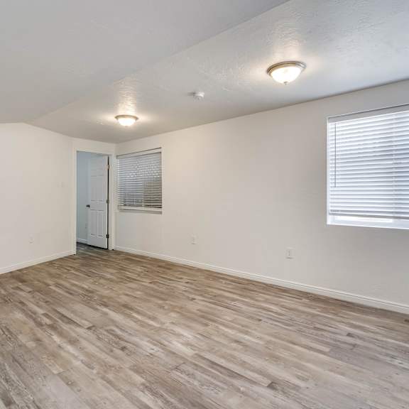 the living room of an apartment with wood flooring and white walls