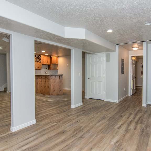 an empty living room and kitchen with wood flooring and white walls