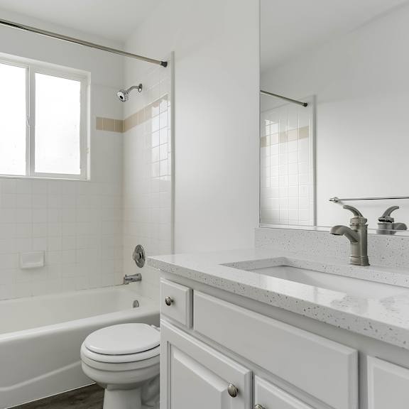 a white bathroom with a toilet, sink, and bathtub.