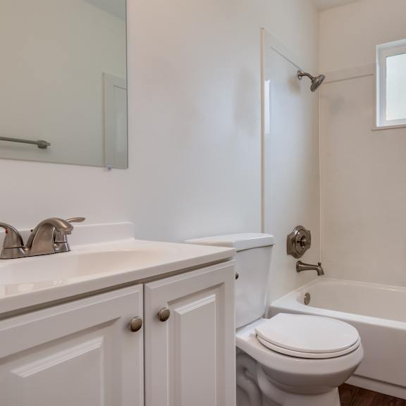 a white bathroom with toilet shower and vanity